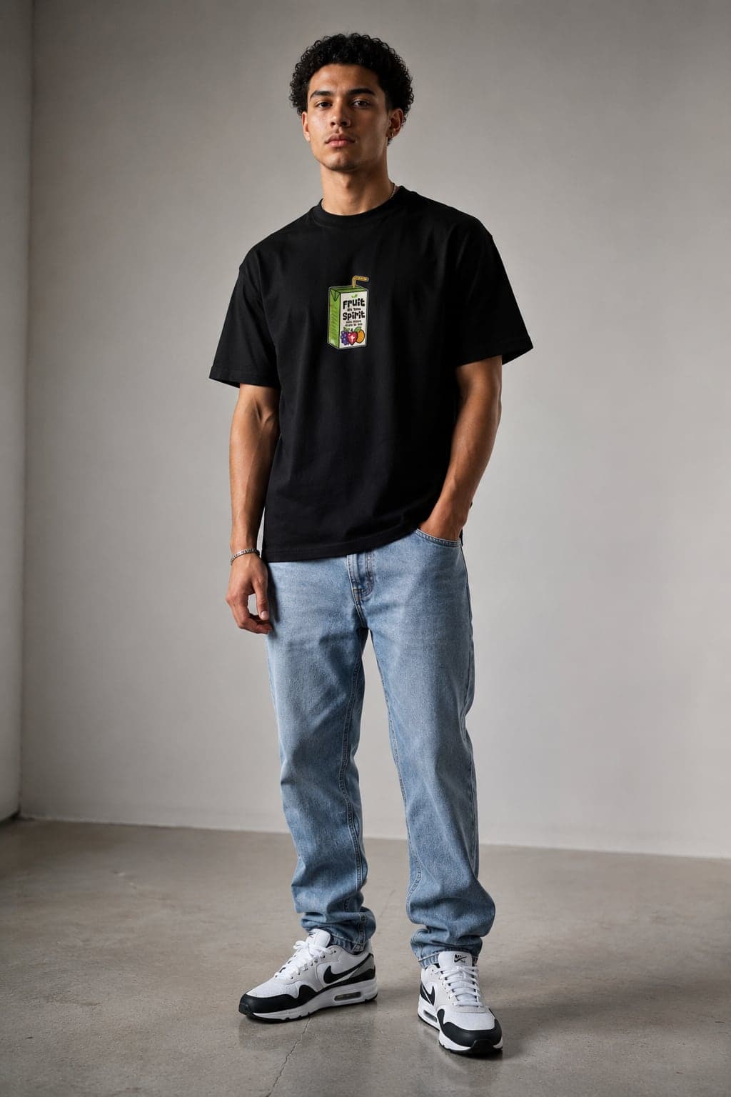 Model wearing the black Fruit Of The Spirit T-Shirt with light-wash jeans